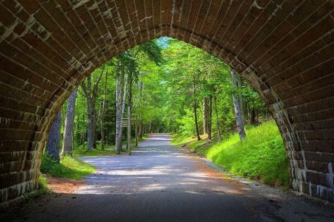 a view of a stone building that has a sign on a brick road