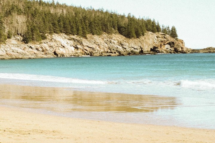 a sandy beach next to a body of water