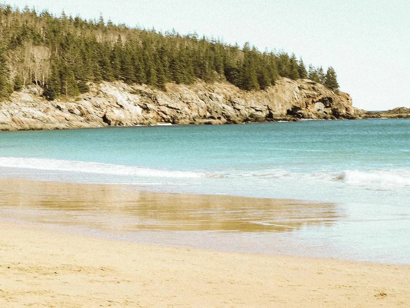 a sandy beach next to a body of water