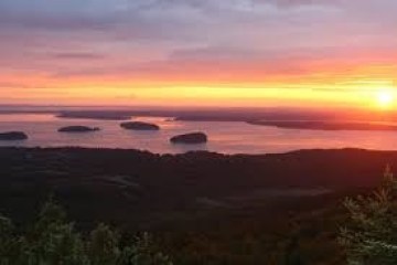 Sunset over ocean with scattered islands and a vibrant sky.