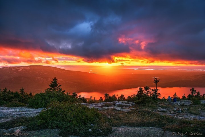 Sunrise over mountains and lake, dramatic clouds and vibrant colors.
