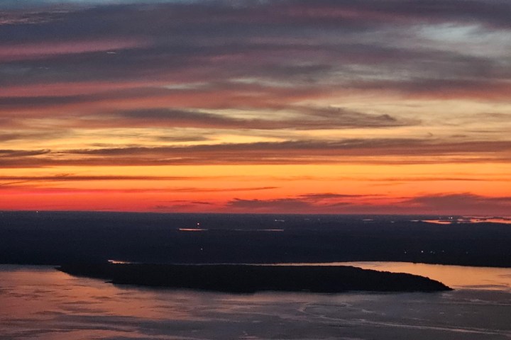 Colorful sunset over a body of water with silhouetted islands and clouds.